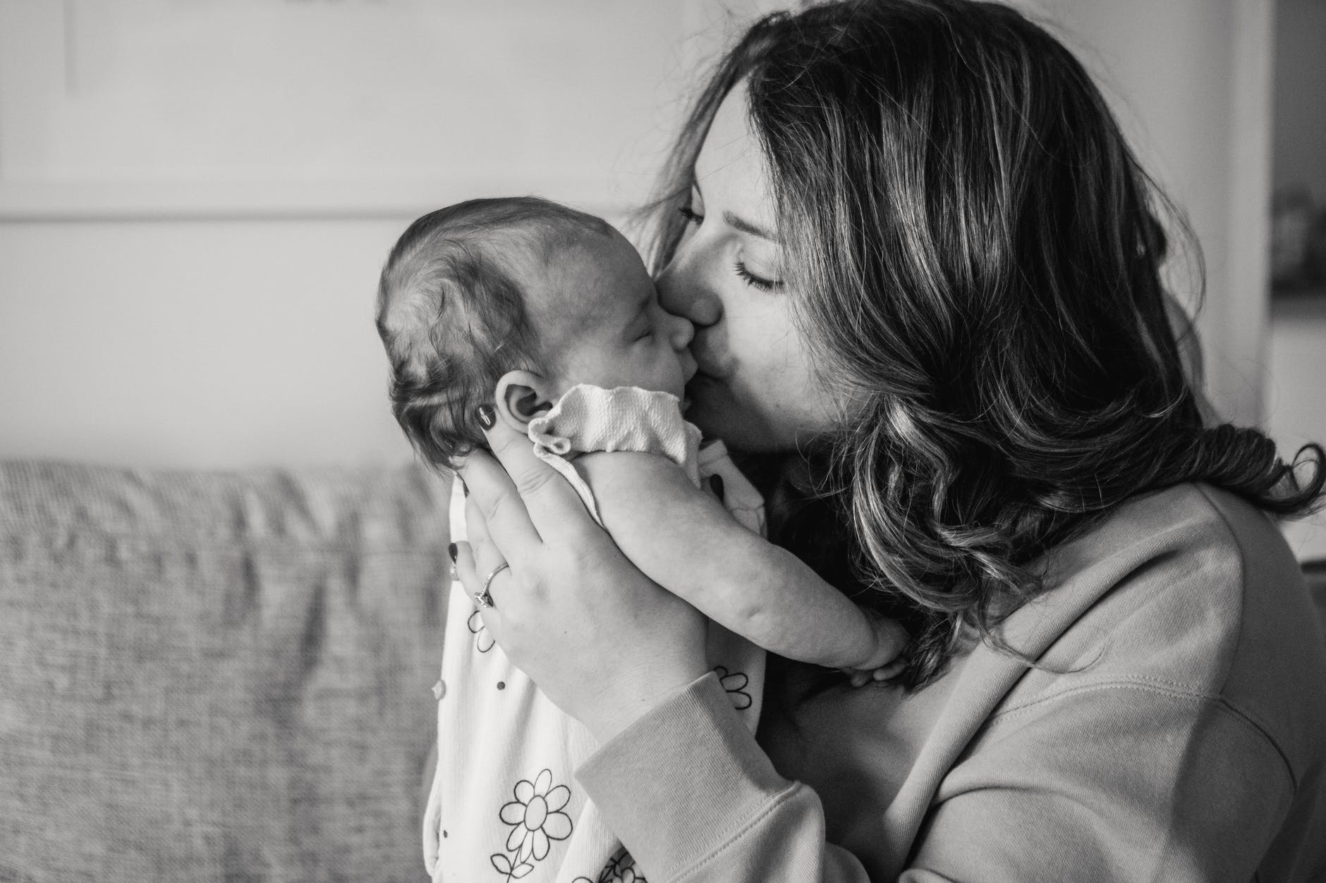 grayscale photo of woman kissing a baby