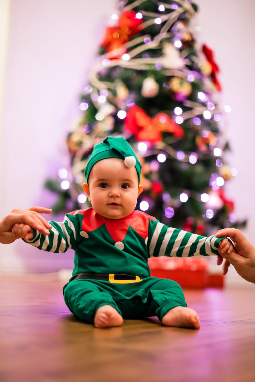 cute baby sitting on floor in elf costume during christmas celebration